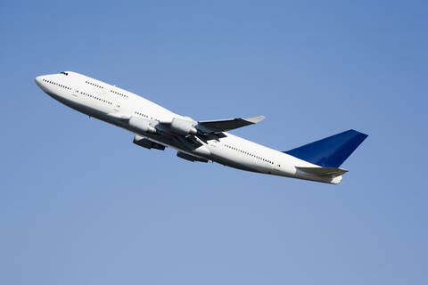 Flugzeug fliegt gegen blauen Himmel, niedriger Blickwinkel, lizenzfreies Stockfoto