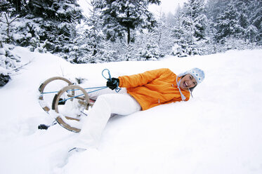 Young woman falling from sledge, smiling - HHF00486