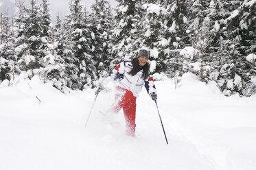 Junge Frau beim Schneeschuhwandern, lachend - HHF00478