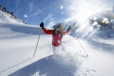 Junge Frau beim Skifahren in den Bergen, lächelnd - HHF00467