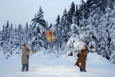 Couple playing with Christmas gift in snow - HHF00459