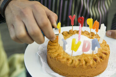 Man igniting birthday cake candles, close-up - WEST01525