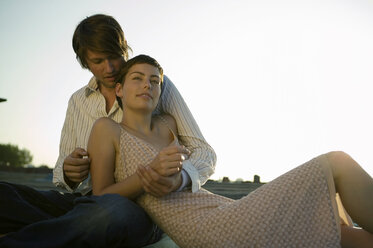 Young couple sitting with sky in background - WEST01493