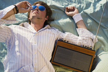 Junger Mann entspannt sich auf einer Decke und trägt eine Sonnenbrille - WEST01480