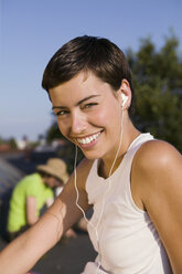 Junge Frau hört MP3-Player, lächelnd, Porträt, Nahaufnahme - WEST01479