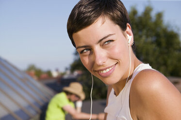 Junge Frau hört einen MP3-Player, lächelnd, Nahaufnahme - WEST01478
