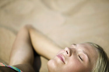 Woman relaxing on beach, eyes closed, (focus on foreground) - WESTF01805