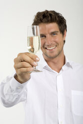 Junger Mann mit einem Glas Champagner in der Hand, Nahaufnahme, Porträt - WESTF01642
