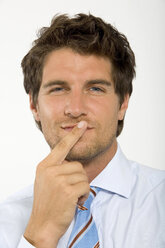 Young businessman with finger on lips, smiling, close-up, portrait - WESTF01632