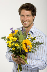 Young man holding bouquet of flowers, smiling, close-up, portrait - WESTF01599