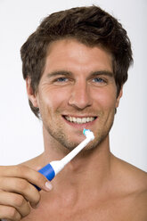 Junger Mann hält elektrische Zahnbürste - WESTF01584