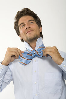 Young businessman getting ready, knotting tie, close-up - WESTF01583