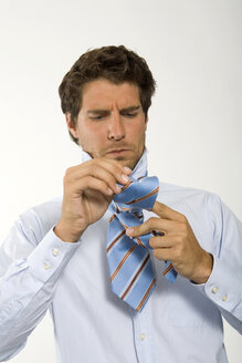 Young businessman getting ready, knotting tie, close-up - WESTF01582