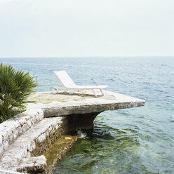 Italien, Lago di Garda, Liegestuhl auf Felsvorsprung - UKF00088