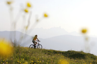 Österreich, Frau fährt Fahrrad auf einer Wiese - HHF00570