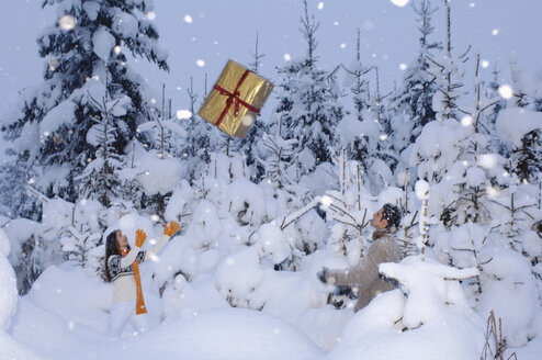 Paar im Schnee wirft sich gegenseitig Geschenke zu - HHF00559