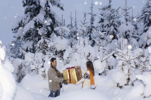 Junges Paar hält Geschenk im Schnee - HHF00553