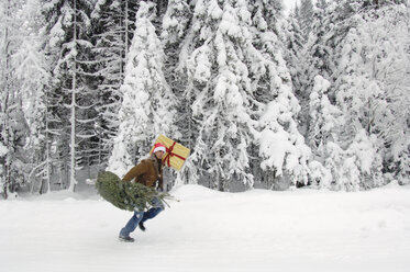 Man in snow, carrying Christmas tree - HHF00529