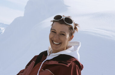 Young woman sitting in snow, smiling, close-up - HHF00449
