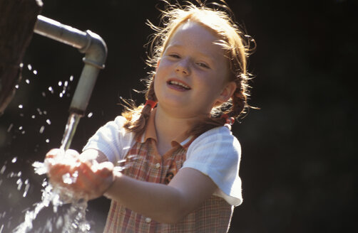 Lächelndes Mädchen, das auf einem Springbrunnen spielt - HHF00433