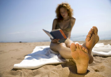 Junge Frau am Strand, die ein Buch liest - WESTF01753