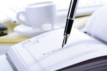 Tagebuch und Stift, im Hintergrund eine Tasse Kaffee - 04669CS-U