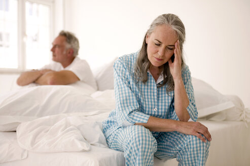 Älteres Paar auf dem Bett sitzend (Fokus auf Frau im Vordergrund mit Kopf in den Händen) - WESTF01967