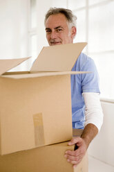 Mature man holding carton, portrait, smiling - WESTF01904