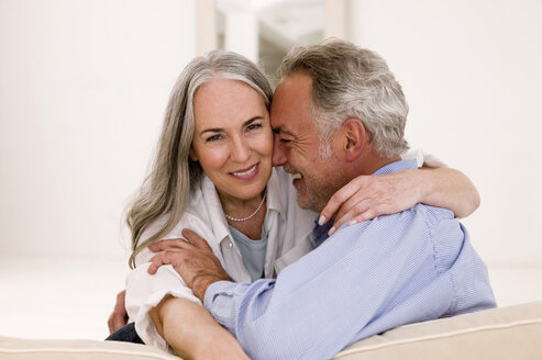 Mature couple embracing on sofa, smiling - WESTF01888