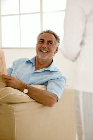 Älteres Paar im Wohnzimmer, Mann schaut Frau an, lächelnd, lizenzfreies Stockfoto