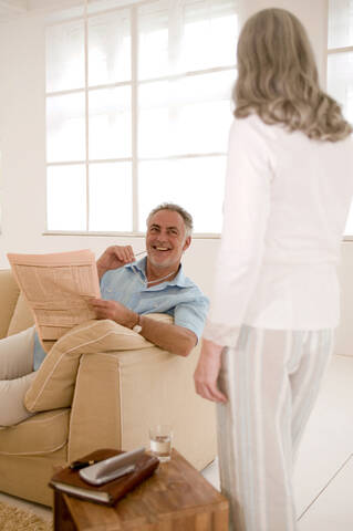 Älteres Paar im Wohnzimmer, Mann schaut Frau an, lächelnd, lizenzfreies Stockfoto