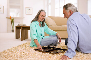 Mature couple playing backgammon in living room - WESTF01858