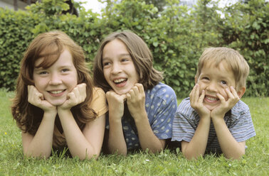 Children lying in meadow in garden, portrait - NHF00216