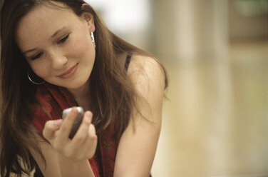 Young girl holding mobile phone, portrait - NHF00196