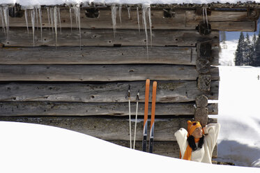 Frau sitzt vor einer Berghütte - HHF00713