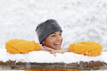Junge Frau im Schnee, an ein Holzgeländer gelehnt - HHF00685