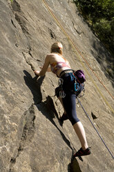 Young woman rock climbing, low angle view - WESTF02378