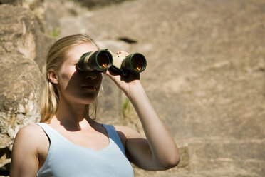 Young woman looking through field glass - WESTF02375