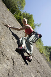 Junge Frau klettert an einer Kletterwand - WESTF02371