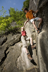 Young couple rock climbing, low angle view - WESTF02364