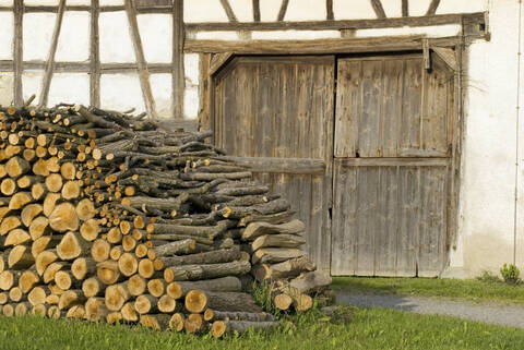 Brennholzstapel vor einem Fachwerkhaus, lizenzfreies Stockfoto