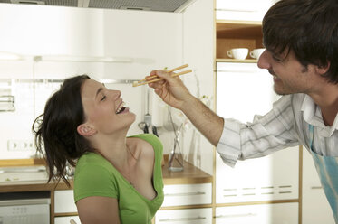 Man feeding woman with chopsticks, smiling - WESTF02192