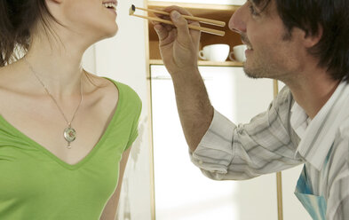 Man feeding woman with chopsticks, smiling - WESTF02191