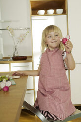 Girl (4-5) in kitchen, holding radish, close-up - WESTF02177