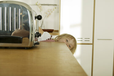 Mädchen (4-5) versteckt sich hinter Küchenarbeitsplatte, Nahaufnahme, Porträt - WESTF02133