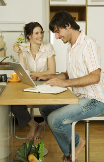 Junges Paar in der Küche, Mann mit Laptop, lächelnd - WESTF02074