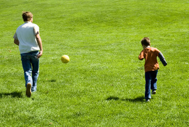 Vater und Sohn (4-7) spielen Fußball im Park, Rückansicht - WESTF02335