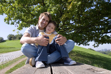 Vater und Sohn (4-7) sitzen auf einer Bank, Porträt - WESTF02298