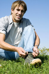 Mid adult man tying shoe, portrait, close-up - WESTF02250