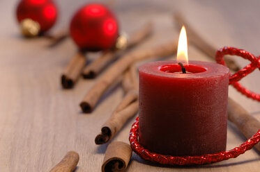 Weihnachtsdekoration mit brennender Kerze und Zimtstangen - ASF02504